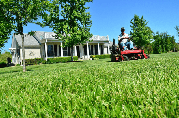 landscape maintenance crew member mowing a nice lawn