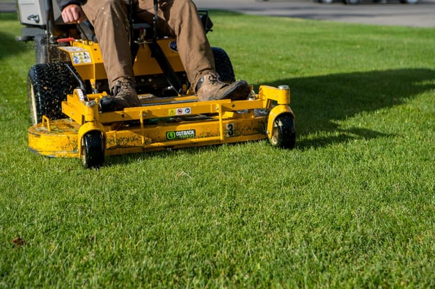 lawn care technician mowing grass
