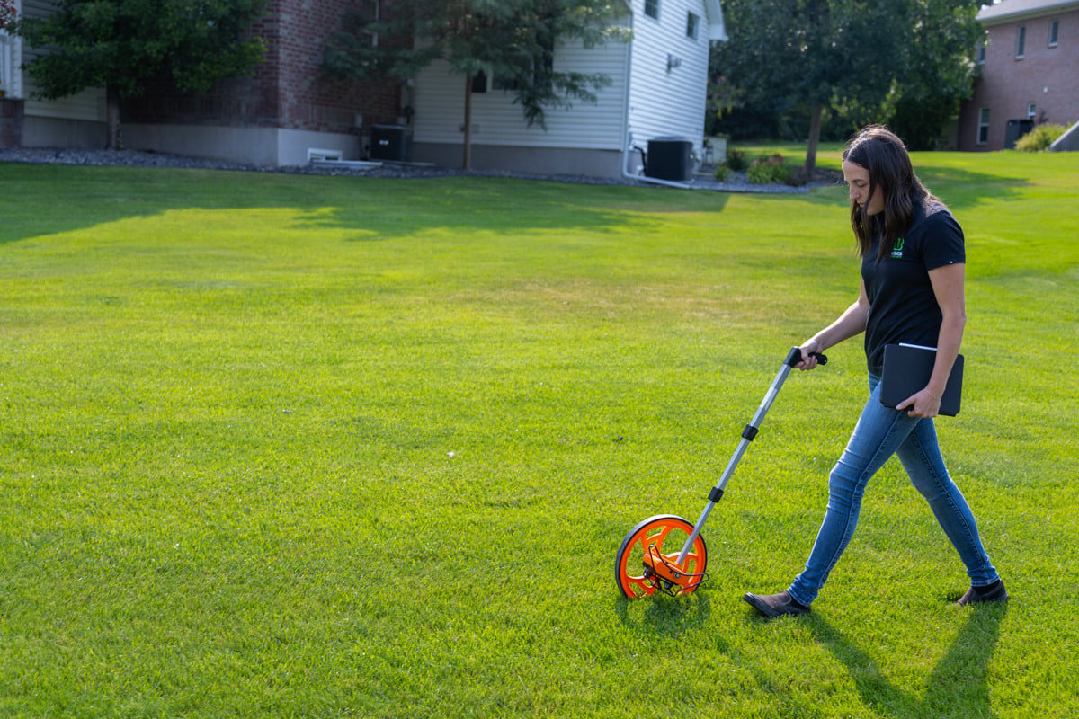 landscape designer measuring a project with a measuring wheel in a nice idaho falls backyard