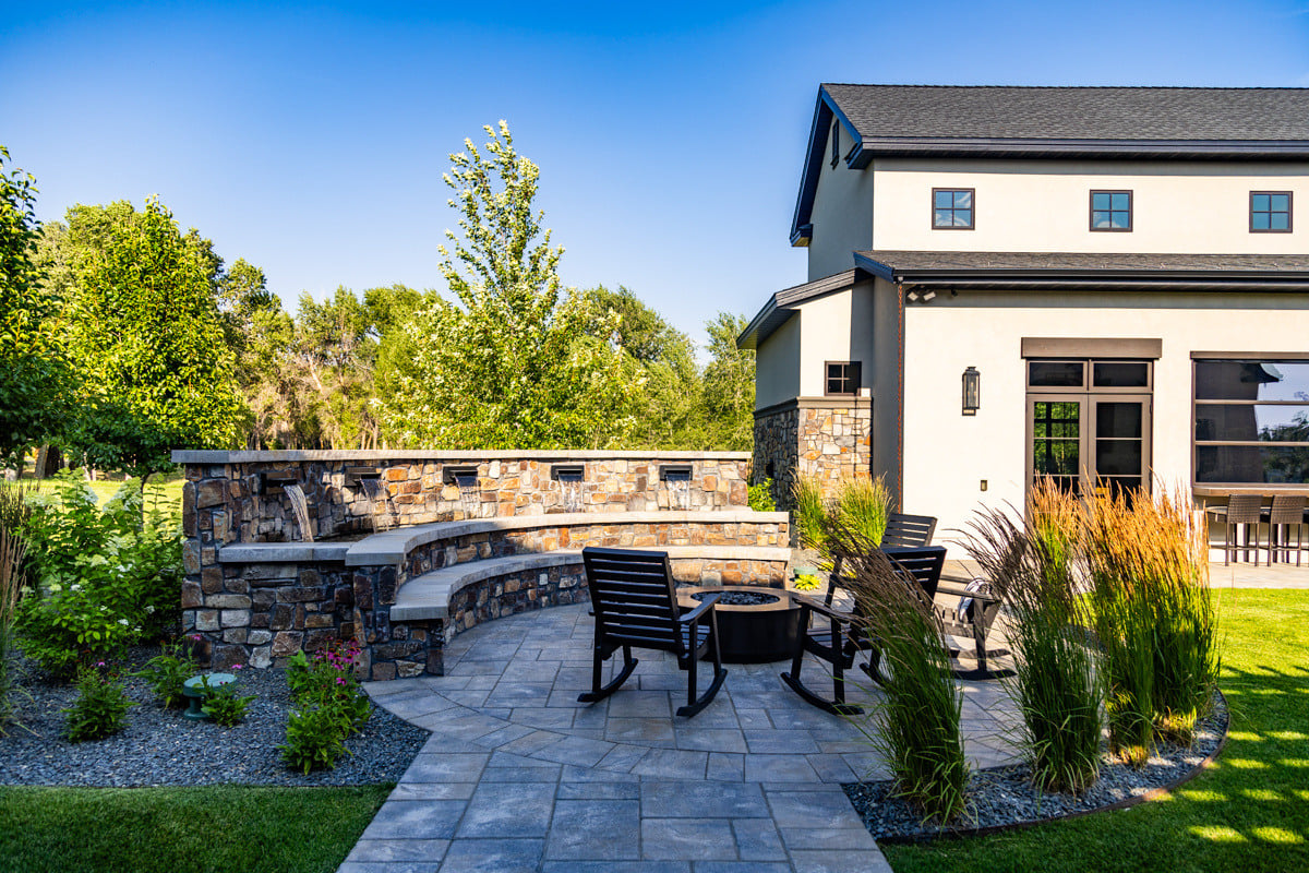 patio firepit chairs seating plants grass turf green lawn water feature waterfall home house gravel wall