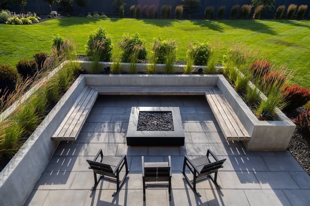 patio seating bench firepit plants grass shrubs raised planters chairs green grass turf lawn nice