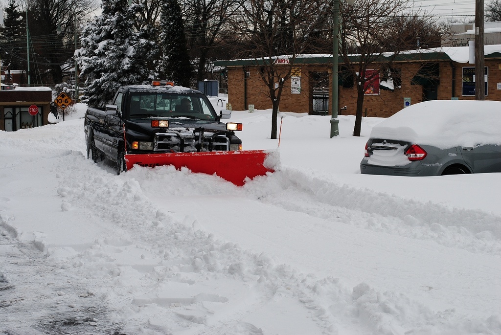 truck plows snow in commercial parking lot