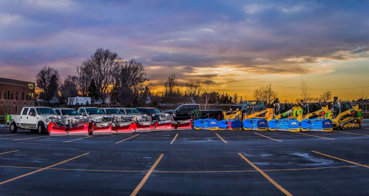 snow removal trucks and equipment lined up in a parking lot