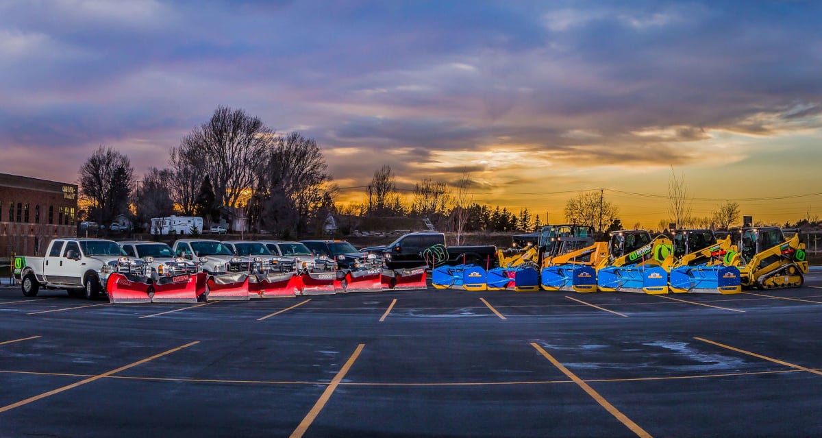 snow removal trucks and pushers in a parking lot
