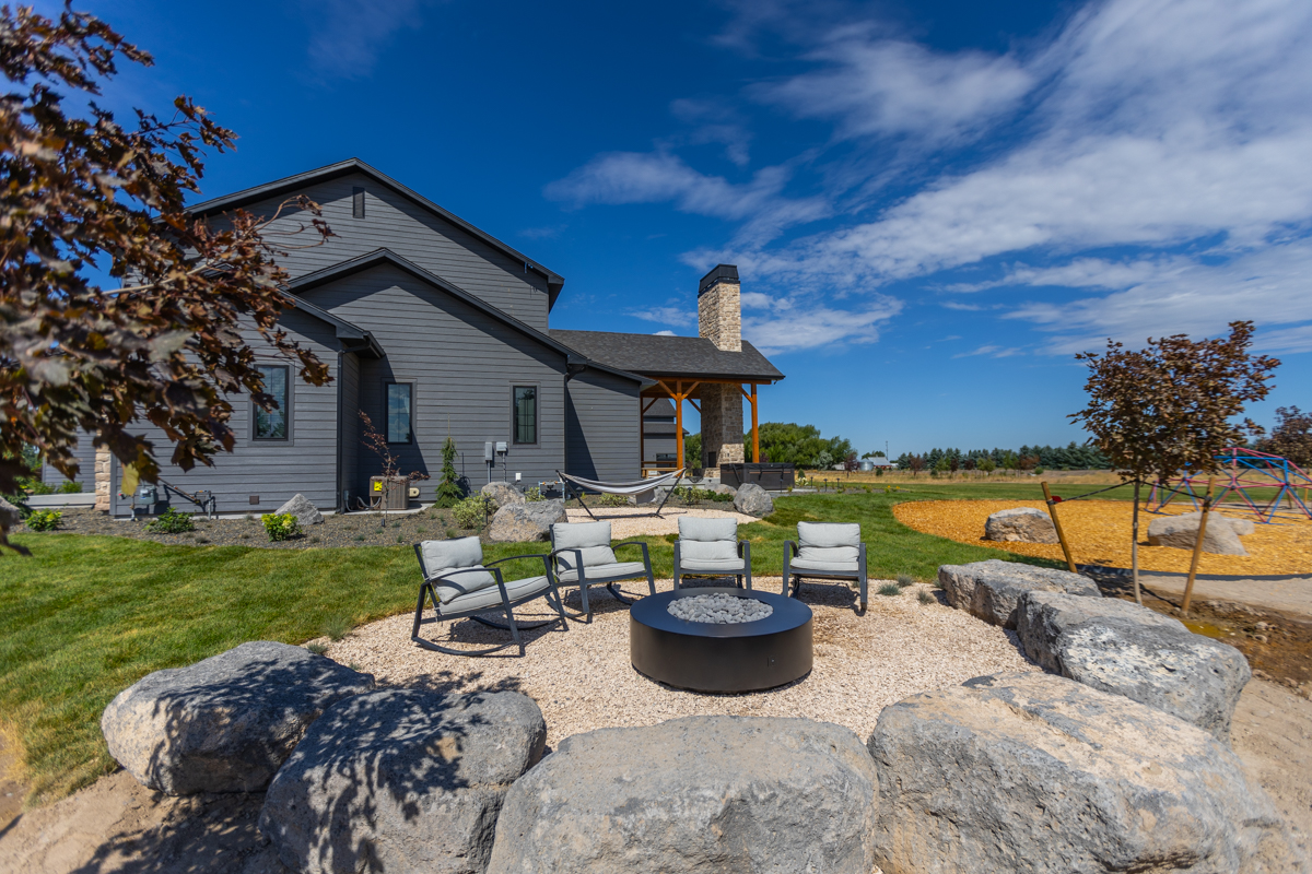 backyard patio boulders fire pit furniture small trees lawn house