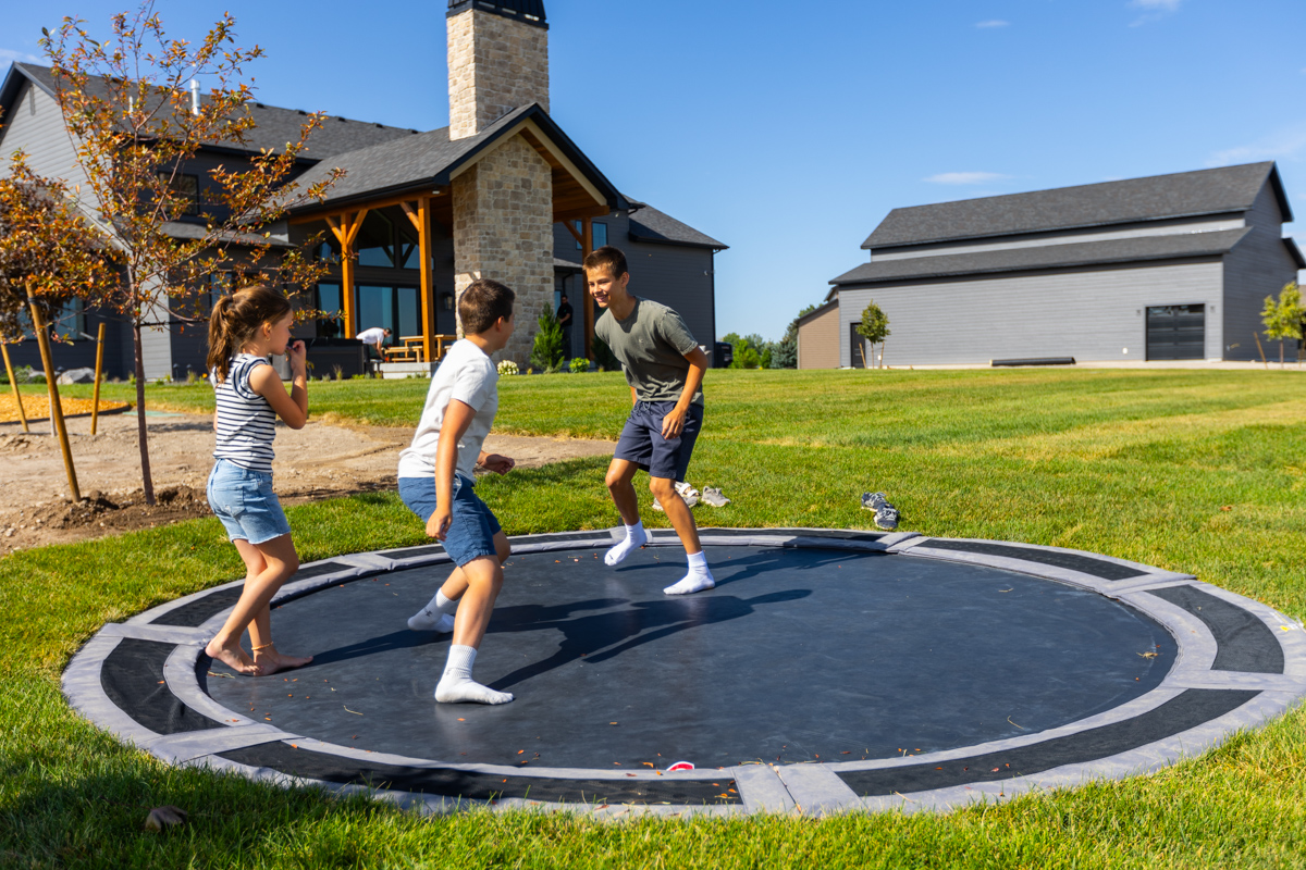 family playing on an in-ground trampoline in a nice idaho falls backyard