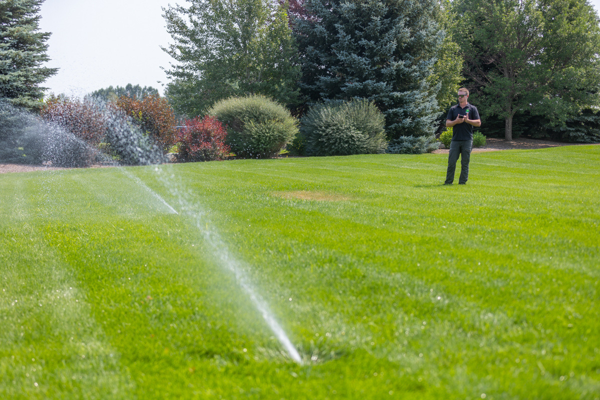 irrigation technician inspecting a lawn sprinkler system in an idaho falls lawn