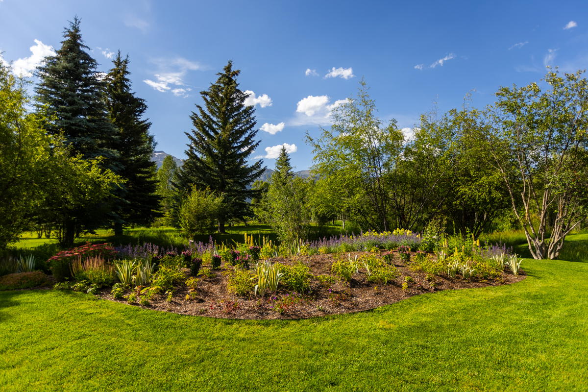 nicely landscaped planting bed with perennials shrubs and large trees in an idaho falls mountain landscape